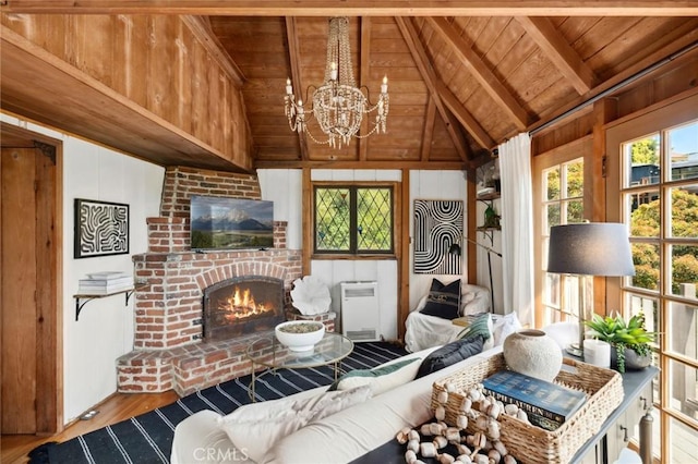 living area with wood ceiling, a brick fireplace, wood finished floors, an inviting chandelier, and vaulted ceiling with beams