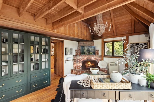 bedroom with a brick fireplace, light wood-style floors, vaulted ceiling with beams, a chandelier, and wooden ceiling
