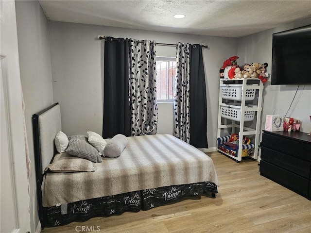 bedroom with recessed lighting, a textured ceiling, and wood finished floors