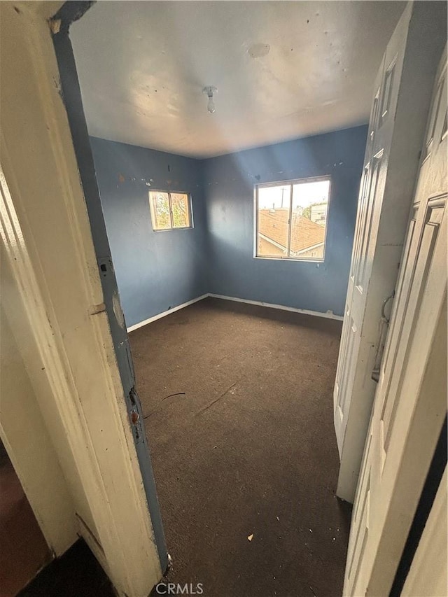 unfurnished bedroom featuring baseboards and multiple windows