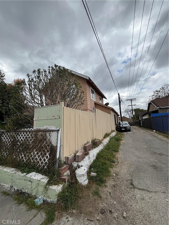 view of side of property featuring fence and aphalt driveway