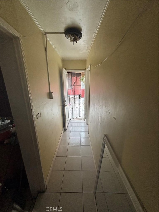 corridor featuring baseboards and light tile patterned flooring