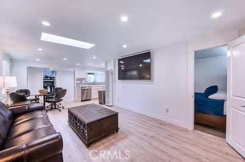 living room with recessed lighting, light wood-style flooring, baseboards, and a skylight