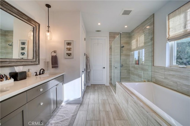 bathroom with double vanity, a shower stall, a bath, and visible vents
