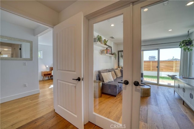 hallway with french doors, recessed lighting, a healthy amount of sunlight, and hardwood / wood-style floors