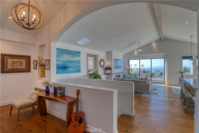 corridor with a notable chandelier, lofted ceiling with beams, wood-type flooring, arched walkways, and baseboards