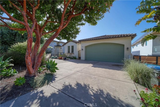 mediterranean / spanish home with a garage, stucco siding, a tiled roof, and driveway