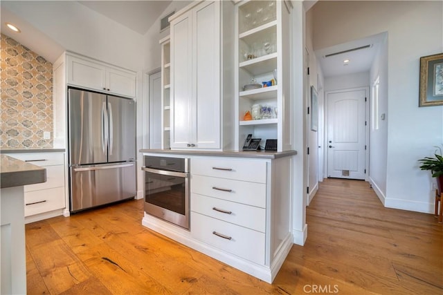 kitchen featuring light wood-style floors, appliances with stainless steel finishes, open shelves, and white cabinetry
