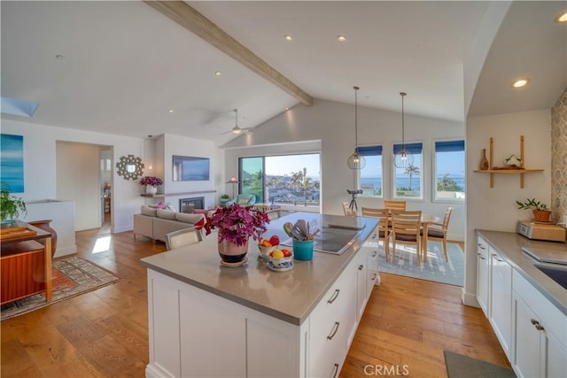 kitchen featuring a ceiling fan, lofted ceiling with beams, white cabinetry, and light wood finished floors