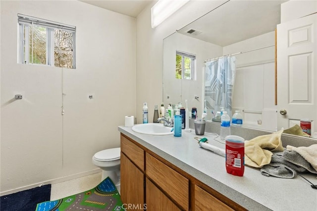 full bath featuring vanity, toilet, a shower with shower curtain, baseboards, and visible vents