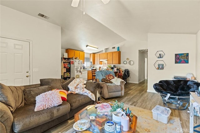living area featuring ceiling fan, visible vents, vaulted ceiling, light wood-type flooring, and baseboards