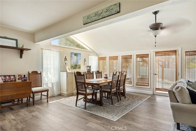 dining space featuring vaulted ceiling, a ceiling fan, and light wood-style flooring