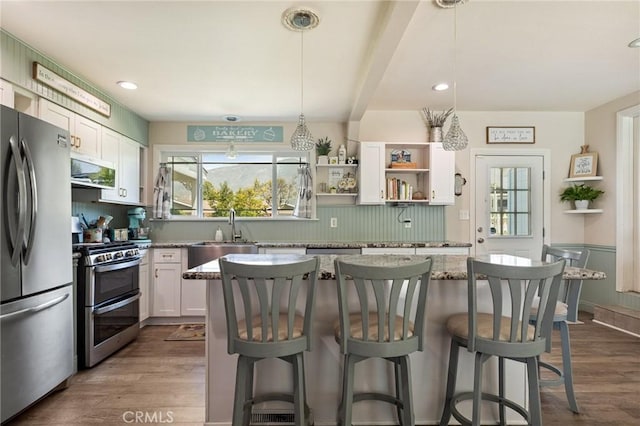 kitchen featuring dark wood-style floors, appliances with stainless steel finishes, a breakfast bar, and a sink