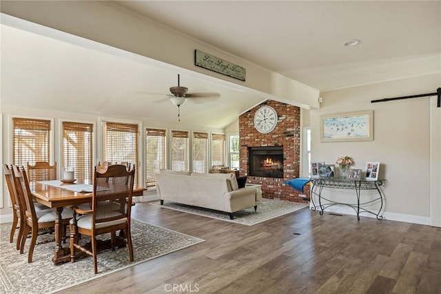 11414 Golden Gate Dr, Yucaipa, CA 92399 - dining area with wood finished floors, a brick fireplace, a barn door, a ceiling fan, and baseboards