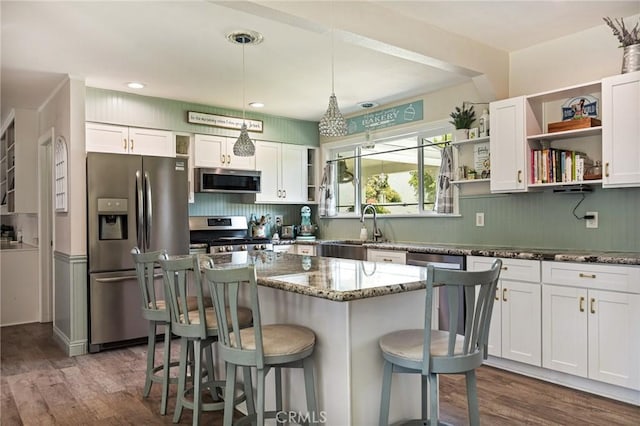 11414 Golden Gate Dr, Yucaipa, CA 92399 - kitchen featuring appliances with stainless steel finishes, open shelves, a sink, a breakfast bar, and dark stone counters