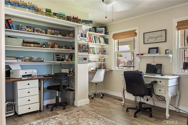 office space with crown molding, baseboards, built in desk, and wood finished floors