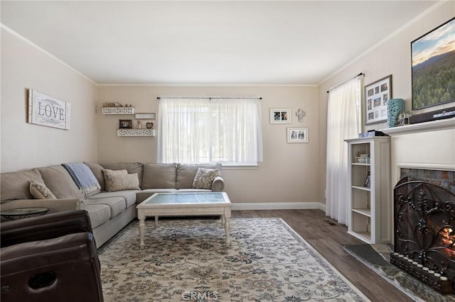 living area with crown molding, baseboards, wood finished floors, and a warm lit fireplace