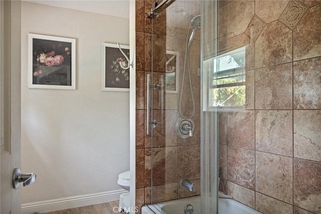 full bath featuring baseboards, combined bath / shower with glass door, and toilet