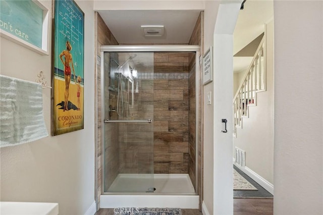 bathroom with baseboards, a shower stall, and visible vents
