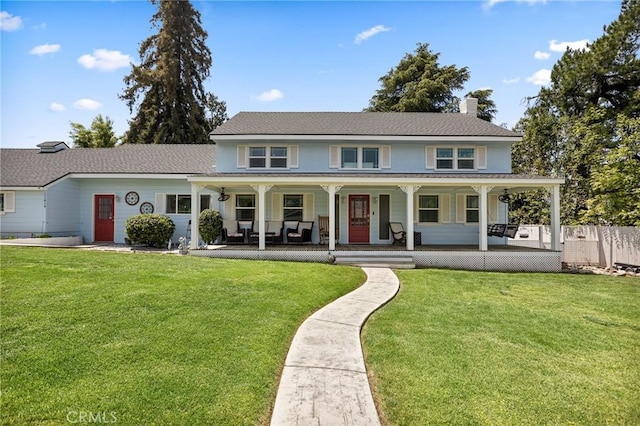 view of front of home with a porch, fence, a chimney, and a front yard