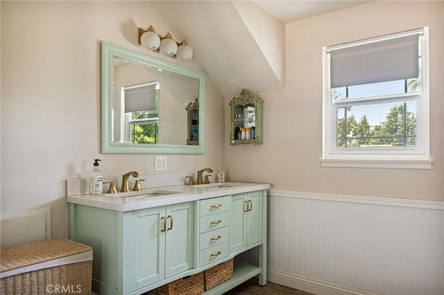 bathroom featuring double vanity, a sink, wainscoting, and a wealth of natural light