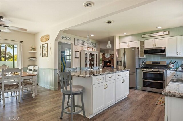 11414 Golden Gate Dr, Yucaipa, CA 92399 - kitchen with stainless steel appliances, ceiling fan, light stone countertops, a wainscoted wall, and white cabinetry