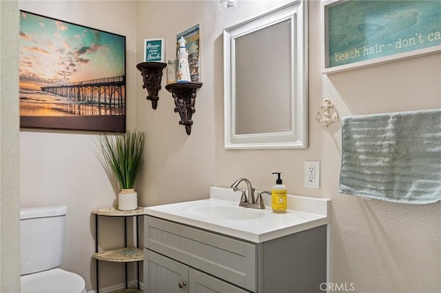 half bathroom featuring vanity and toilet