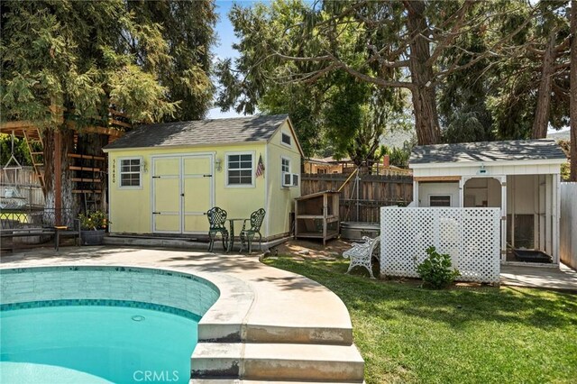 view of pool with a storage shed, a fenced in pool, a fenced backyard, an outbuilding, and a lawn