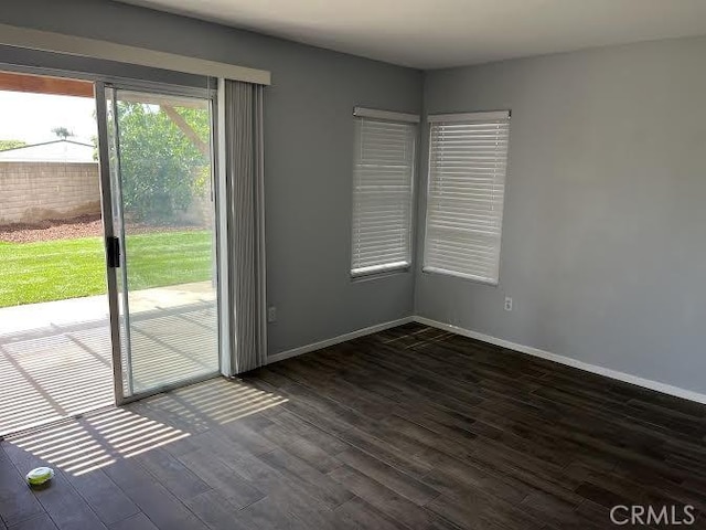 empty room featuring baseboards and dark wood finished floors