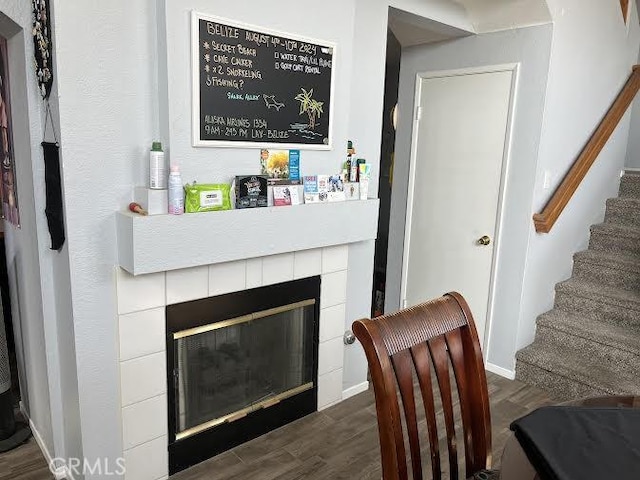 interior space featuring stairway, baseboards, a tile fireplace, and dark wood-type flooring