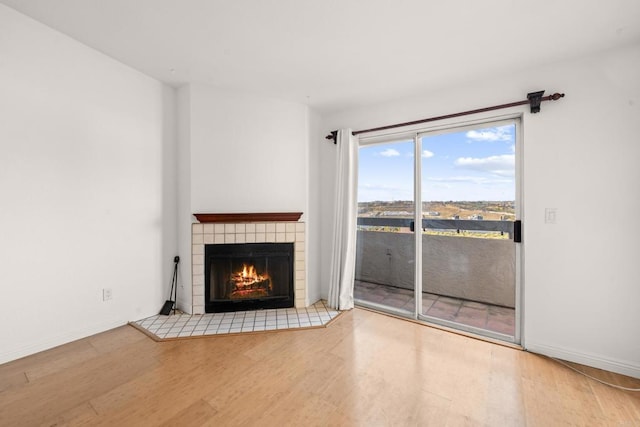 unfurnished living room with baseboards, wood finished floors, and a tile fireplace