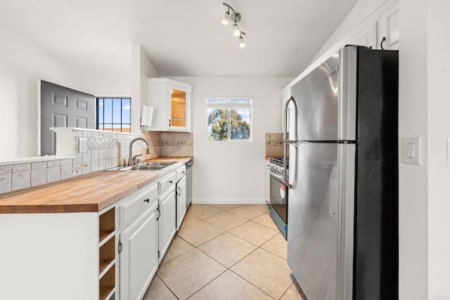 kitchen with appliances with stainless steel finishes, decorative backsplash, a sink, and a healthy amount of sunlight