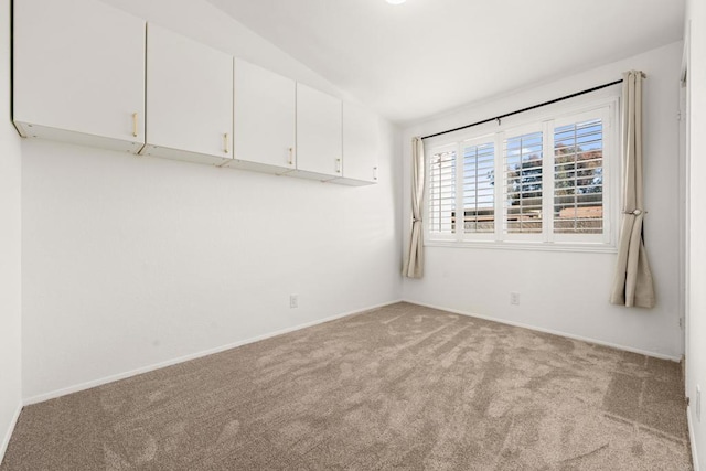 unfurnished room with baseboards, lofted ceiling, and light colored carpet