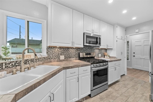 18012 Falda Ave, Torrance, CA 90504 - kitchen featuring a sink, appliances with stainless steel finishes, decorative backsplash, and white cabinetry