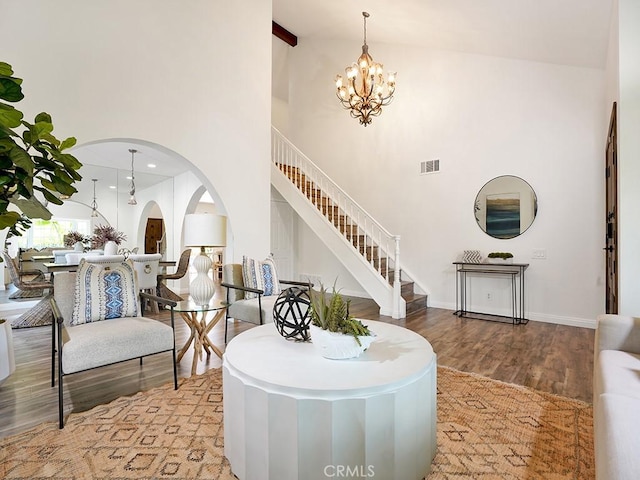 living room with visible vents, wood finished floors, a high ceiling, stairway, and a notable chandelier