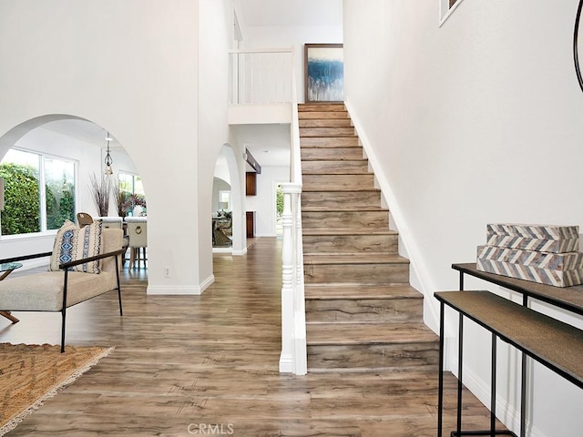 23872 Lagarto, Mission Viejo, CA 92691 - staircase featuring a towering ceiling, arched walkways, wood finished floors, and baseboards