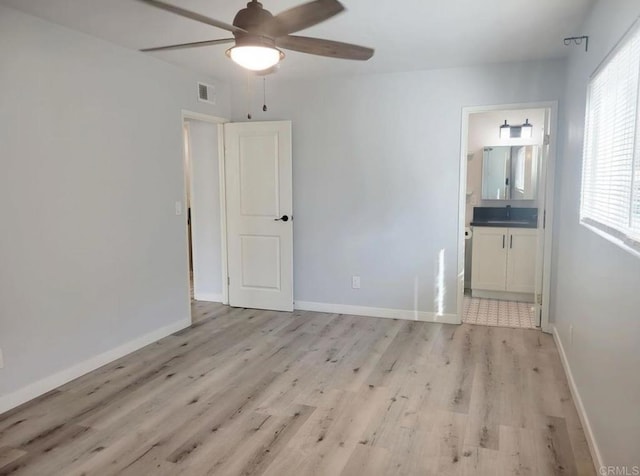 spare room with a sink, light wood-style flooring, a ceiling fan, baseboards, and visible vents