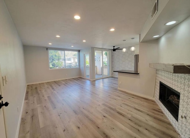 unfurnished living room with light wood-style floors, a tiled fireplace, recessed lighting, baseboards, and visible vents