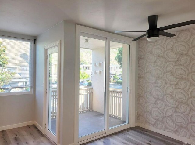 doorway featuring baseboards, light wood-style flooring, and ceiling fan