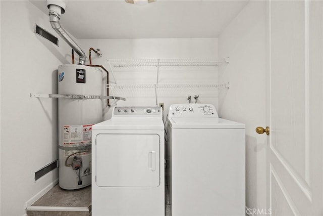 clothes washing area with laundry area, baseboards, water heater, and washer and dryer