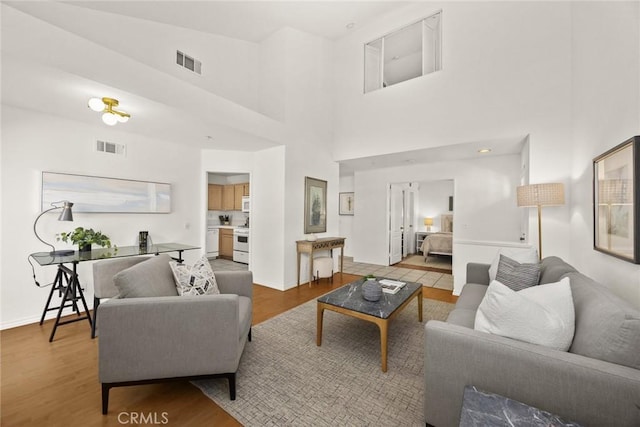 living area with visible vents, baseboards, and wood finished floors