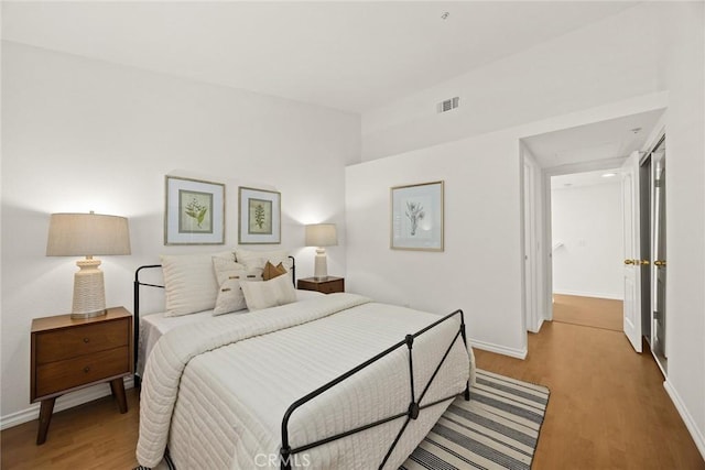 bedroom with baseboards, wood finished floors, and visible vents
