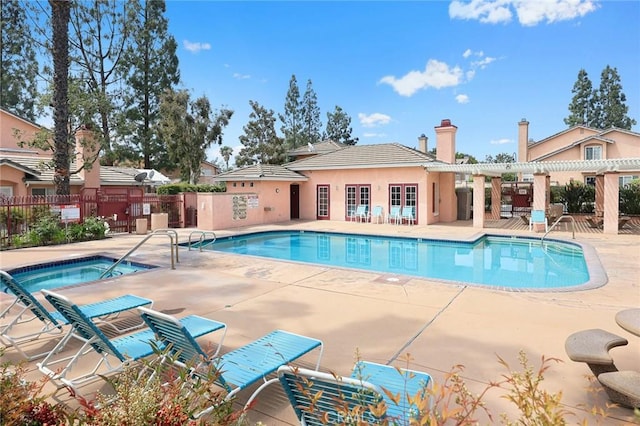 pool featuring a patio, fence, and a community hot tub
