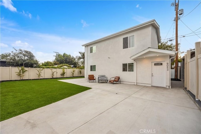 back of property featuring a fenced backyard, stucco siding, a lawn, and a patio area