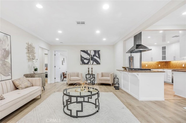 living room featuring recessed lighting, visible vents, ornamental molding, and light wood-type flooring
