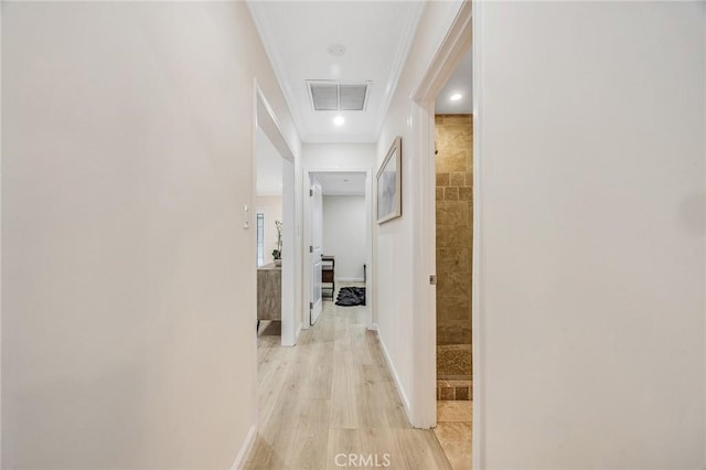 corridor featuring crown molding, baseboards, light wood finished floors, and visible vents