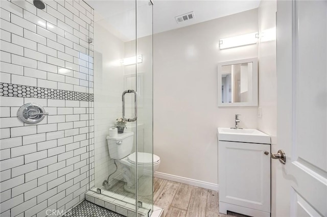 bathroom featuring visible vents, a stall shower, wood finished floors, vanity, and toilet