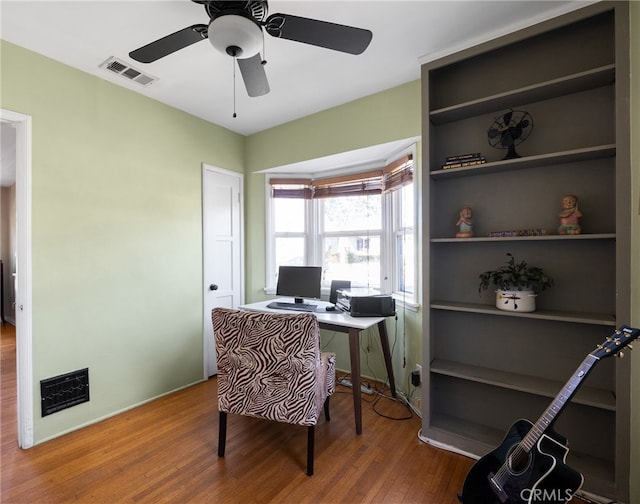 office space featuring ceiling fan, visible vents, and wood finished floors