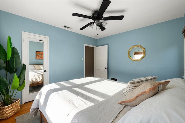 bedroom with ceiling fan, wood finished floors, and visible vents