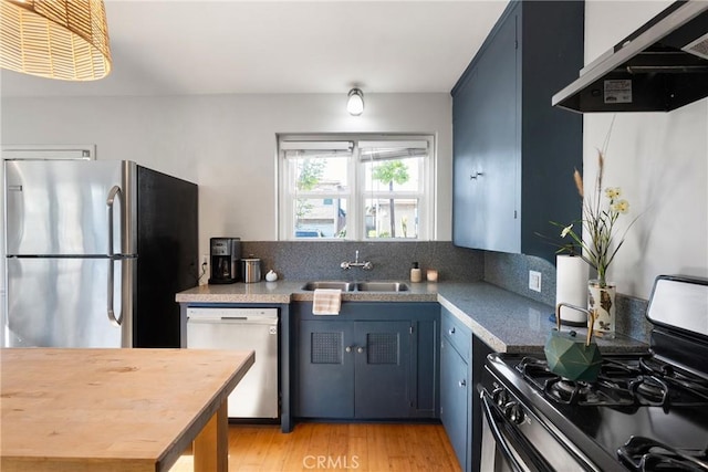 kitchen featuring blue cabinets, a sink, light wood finished floors, under cabinet range hood, and stainless steel appliances